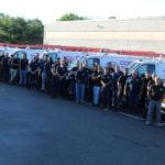 Employees in front of fleet of cars